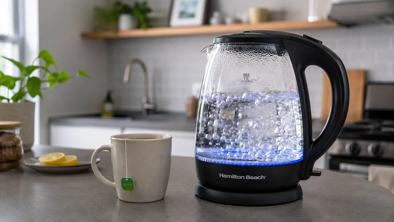 Hand pressing the power button on the Hamilton Beach 1-liter electric kettle